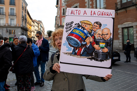 A protester carries a placard with caricatures of Donald Trump, drinking from an oil barrel during a demonstration. Internationalist organizations stage a demonstration in front of the Ministry of Foreign Affairs in Madrid to demand an end to the US blockade of Cuba.
