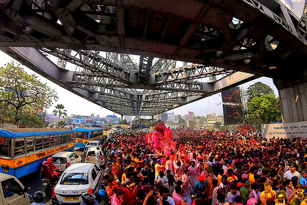 An aerial view of Hindu devotees carrying a Hindu god Satya Narayan on a vintage Rolls Royce car along the Howrah Bridge over the Ganga River during the celebrations of the Hindu spring festival of 'Holi'. Holi, also known as the festival of colors is celebrated to mark the arrival of spring.