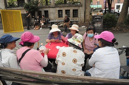 People are seen at a table in a park in Chinatown, Manhattan, New York City.