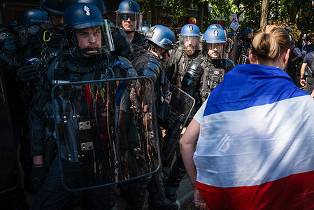 A protester draped in a French flag walks past riot police during the rally. Thousands of protesters marched from Place d’Italie to Place de la Nation during May Day demonstrations, held annually on 1 May to mark International Labor Day and show union solidarity for workers' rights. This year’s protest drew large crowds amid calls for better working conditions and social justice. Authorities deployed 7,400 police officers across Paris in anticipation of potential unrest.
