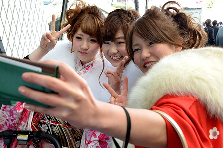 Japanese women wearing kimonos seen taking commemorative photos during a Coming of Age Day ceremony.