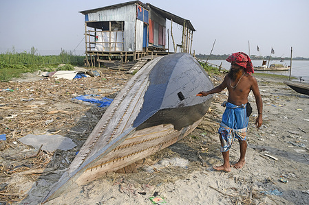 Shah Alam applies paint to his boat at Laharhat, Barishal. Climate Change Deepens Hardship for the Manta Community in Barishal, Bangladesh.