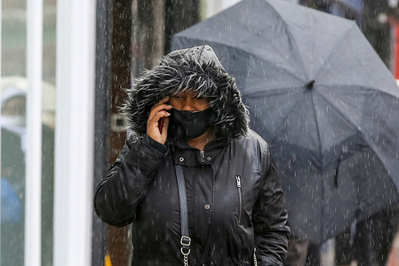 A woman speaking on her mobile phone during heavy rainfall in the capital.