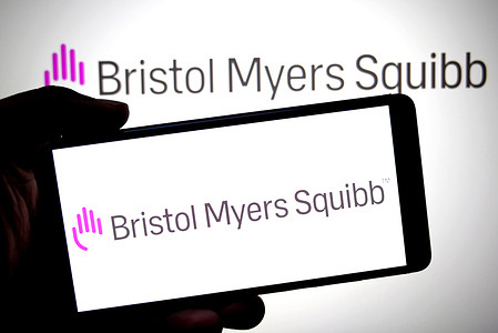 In this photo illustration, a Bristol Myers Squibb logo is seen displayed on a smartphone and in the background.