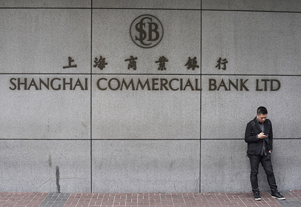 A man stands by a Shanghai Commercial Bank LTD branch in Mong Kok, Hong Kong.