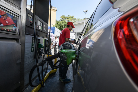 A employee seen filling up the tank of a car during a simulation day to test a new device.
The Government of the Bolivarian Republic of Venezuela performed simulation in the gas stations of the state oil company, PDVSA (Petroleos de Venezuela), where the employees will use a device to control the sale and consumption of gasoline.
Users must use an identity card issued by the government of President Nicolas Maduro known as "Carnet de la Patria" to get the national price. Those who do not have the card or decide not to have it for personal reason, must pay for the fuel at an international price. For now, the national government has not yet announced the price of gasoline.
