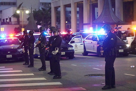 Police officers close roads at downtown when the curfew begins. In Los Angeles, ongoing protests against recent ICE raids have escalated into intense clashes between demonstrators and law enforcement. Tensions continued on the night of June 10, prompting Mayor Karen Bass to declare a state of emergency and impose a citywide curfew—the first since 1992. Protesters gathered outside the downtown federal building, where officers used stun grenades and pepper spray to disperse the crowds. Dozens blocked the 101 freeway before being cleared by highway patrol. As looting and property damage surged overnight, nearly 200 arrests were made. National Guard units were deployed, and law enforcement helicopters hovered above while journalists faced threats of arrest. President Trump ordered reinforcements, including 4,000 National Guards and 700 Marines, branding the protestors as insurgents and hinting at invoking the Insurrection Act.