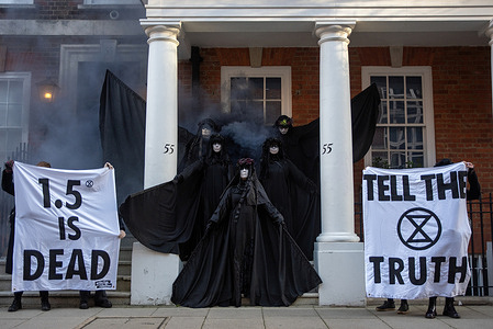 Oil slickers (slow motion performers) pose for photos outside the 55 Tufton Street (it is owned by a right-wing climate skeptical lobby group) during the rally. Extinction Rebellion campaigners called on political leaders for failing to meet climate commitments, in central London, UK. Because of the government inaction over 1.5-degree target. The 1.5-degree target is the climate goal of limiting the man-made global temperature increase caused by the greenhouse effect.