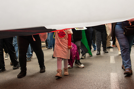 A girl under a large flag wears a t-shirt that reads: Long Live Free Palestine during a demonstration. A demonstration took place on the streets of central Madrid to bid farewell to the new humanitarian flotilla bound for Gaza, which departed today from the port of Barcelona, ​​among other cities. The march was organized by the Global Sumud Spain coalition and concluded with the reading of a manifesto and performances by two choirs.