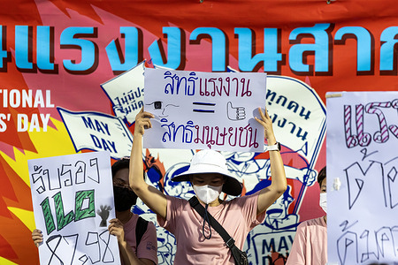 Protesters hold handwritten placards reading “Labor rights = human rights” during a Labor Day rally advocating for workers’ rights and social protections.