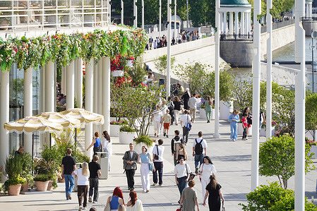 Visitors stroll through Gorky Park along Pushkin Embankment on a sunny day.