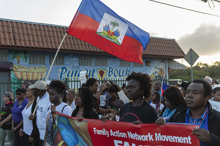 MIAMI, UNITED STATES - JANUARY 13 2020: Members of the Little Haiti community hold a flag and a banner while marching the ceremony at the Little Haiti Cultural centre in Miami.
Haiti marked the 10th anniversary of its greatest tragedy of earthquakes with a low-key commemoration that included private ceremonies, a blood drive and a renewed call for unity from its president.