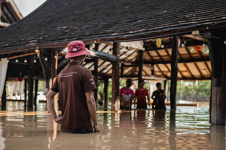 People wade through floodwaters at a riverside area after flash floods in Chiang Mai, northern Thailand. Heavy rains caused flash floods in Chiang Mai, northern Thailand, inundating communities along the Ping River and damaging homes and businesses.