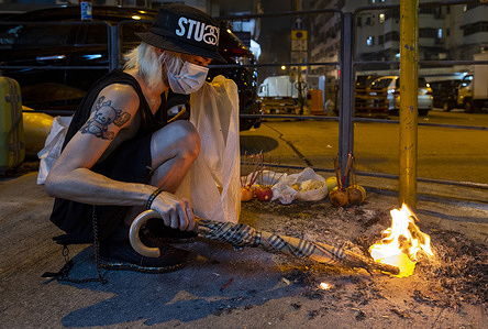 A resident uses an umbrella to keep the fire alive as he burns paper money during the festival.
According to local tradition, the Hungry Ghost Festival is marked believing that the gates of hell will open for the month (July of the Chinese lunar Calendar) and ghosts would roam the streets.