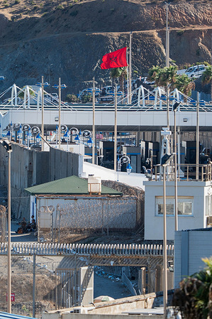 A Moroccan flag flies at the Tarajal border crossing. The city is facing a major migration, humanitarian and security crisis following the mass arrival of around 80,000 people from Morocco through the Tarajal border crossing. The scale of the influx temporarily overwhelmed the Spanish enclave’s border control, identification and reception capacity while large numbers of migrants set up makeshift camps on Trampolín Beach. 
Authorities are working to relocate and identify the remaining migrants while assessing their individual circumstances and the possibility of returning them to Morocco. A large camp has been set up in the Loma de Colmenar district to centralise reception and identification operations and ease pressure on other parts of the city.
