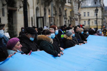 Ukrainians unfurl a huge Ukrainian flag on Rynok Square.
Ukrainians mark the 156th anniversary of the public performance of the Ukrainian national anthem which was first performed on 10 March 1865.They sang the national anthem and unveiled the Ukrainian flag on Rynok Square, in front of the Lviv City Council (Ratusha) Hall.