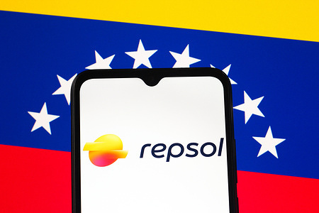 In this photo illustration, the Repsol logo is seen displayed on a smartphone screen and the Venezuelan flag in the background