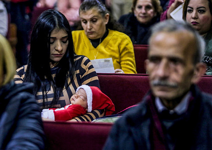 A Christian Palestinian woman carries a baby dressed as Santa Claus as she attends prayers at the Latin Church in Gaza during midnight Christmas mass in Gaza City.