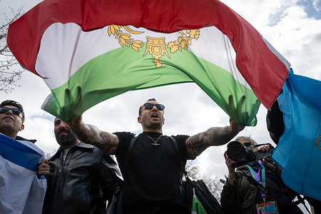 An Iranian protester holds an Iranian Monarchy flag during the rally. Members of the Iranian diaspora staged a counter-protest during a march organized by Together Alliance and House Against Hate in central London, voicing opposition to the participation of groups they accuse of supporting the Iranian government. Counter-protesters displayed Iranian and Israeli flags expressing solidarity with anti-government movements in Iran.