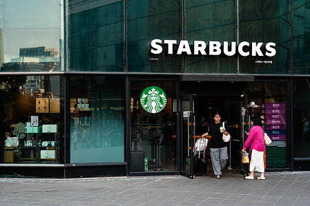 A woman holding a take out coffee walks out of Starbucks in Seoul.