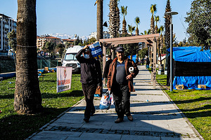 Hatay, Turkey - 14/02/2023 15:47:46: People carrying some relief goods walk past a relief shelter. Turkey and Syria have experienced the worst earthquakes to strike the region in almost a century. A 7.8-magnitude quake struck southeastern Turkey, which was followed by a second quake of 7.7 in northern Syria. More than 30,000 people are reported to have died due to the quakes, and the death toll is still rising.