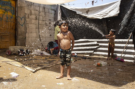 Palestinian children spray water on themselves to cool down on a hot summer day in Khan Yunis, southern Gaza.
