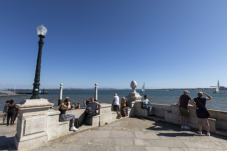 People seen relaxing at the Cais das Colunas pier, overlooking the Tagus river, in Lisbon.
The Cais das Colunas pier was built in the second half of the 19th century. For many years it served as a noble entrance for those arriving in Lisbon by boat. The pier was named after the two columns that can be seen on the side of the main marble steps.