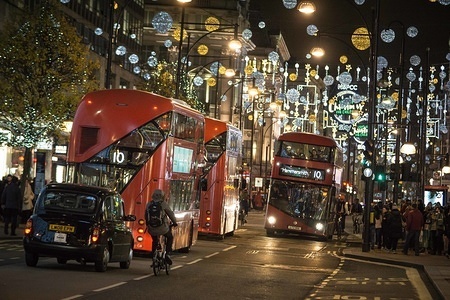 A man seen riding a bicycle on London's Oxford Street with Christmas Decorations in the background during Christmas festive climate in Central London.