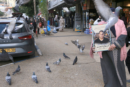 Palestinian mother of prisoner Luay Nimr, who is imprisoned in an Israeli jail, stands among doves of freedom in downtown Nablus in the West Bank during a protest demanding the release of prisoners held by Israel. The Palestinian Information Center reported that the number of Palestinian prisoners exceeded 9,500 in 2025.