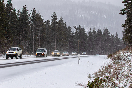 Cars descend a mountain road in winter weather. 
Winter road conditions worsen as snow falls in the mountains. Chains were required on all vehicles except 4-Wheel drive with snow tires.