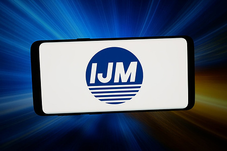 In this photo illustration, the logo of Malaysian company IJM Corporation Berhad is displayed on a smartphone in front of abstract background on computer screen.