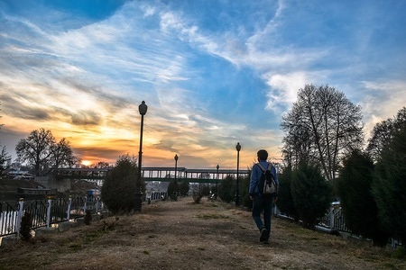 A Kashmiri boy walks in the park at sunset time on a sunny winter day in Srinagar, Indian administered Kashmir. Sunny days continued in Kashmir valley on Monday while the minimum temperature also witnessed an increase of several notches bringing a respite from cold nights.