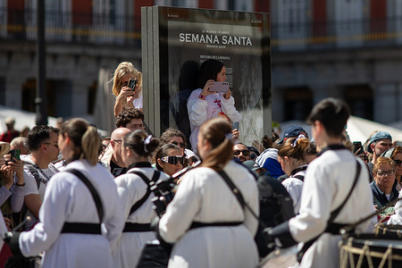 A woman takes a photograph among the spectators during the drum parade in Madrid's Plaza Mayor on Easter Sunday. Madrid concludes Holy Week 2026 this Easter Sunday with the participation of musicians and their drums, belonging to the Brotherhood of the Exaltation of the Holy Cross of Zaragoza, who gathered for a drum parade in the Plaza Mayor.