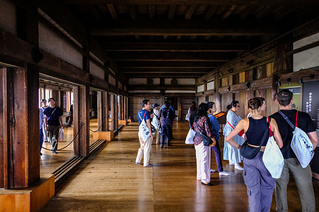 Tourists seen inside the historic interior of Himeji Castle in Himeji city, Hyogo Prefecture, western country. After passing its gates and narrow defensive passageways, visitors climb the main keep's steep wooden staircases to see its preserved timber structure and defensive features, offering a glimpse of its dual role as both residence and stronghold, with entrances and openings designed to slow attackers. Dating to the 14th century, Himeji Castle was expanded to its current form in the early 17th century by Ikeda Terumasa under the Tokugawa shogunate and served as a feudal domain center for nearly three centuries. Its six-story wooden main keep, surrounded by three smaller keeps, gates, walls, and other defensive buildings, is renowned for preserving early 17th-century Japanese architecture and defense systems. Known as White Heron Castle for its white-plastered appearance, it survived wars, fires, and upheavals intact. It was designated a National Treasure and became one of Japan's first UNESCO World Heritage Sites in 1993. According to Himeji City, it drew over 500,000 foreign visitors in fiscal 2024, with English guides and volunteer interpreters available for international visitors.