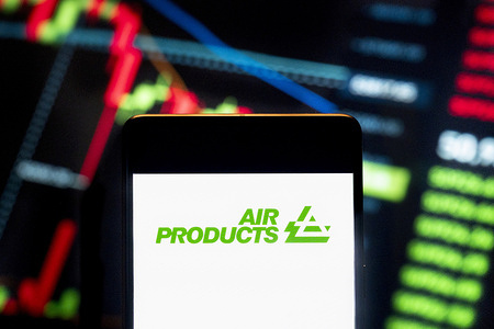 In this photo illustration, the American industrial gases and chemicals corporation, Air Products and Chemicals (NYSE: APD), logo seen displayed on a smartphone with an economic stock exchange index graph in the background.