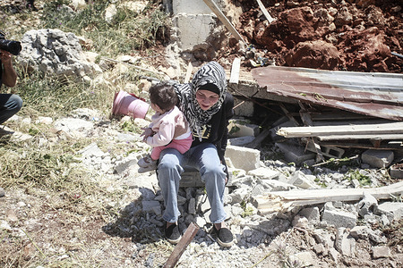 A Palestinian woman carries her child among the rubble of her home, which was destroyed by Israeli forces in the Nablus Al-Jadida neighborhood of the West Bank city of Nablus. Israeli army forces stormed the Old City of Nablus, and in cooperation with Israeli special forces, they killed a Palestinian militant suspected of belonging to the Palestinian "Lions' Den" militant group. Dozens were injured during the clashes.