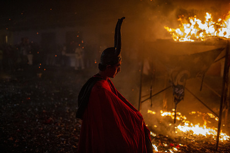 A man dressed as a devil walks past the bonfire, during the Burning of the Devil on the eve of the celebration of the Virgin of the Immaculate Conception, festivities that mark the beginning of Christmas in Guatemala.