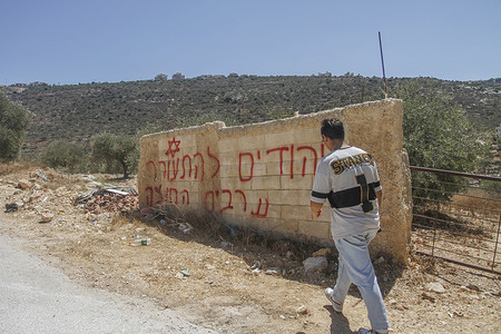 A Palestinian inspects the place where Jewish settlers wrote slogans against Palestinians in the Hebrew language in Marda village, south of the city of Nablus in the West Bank. In the early hours of the morning, settlers wrote these slogans and vandalized Palestinian vehicles.