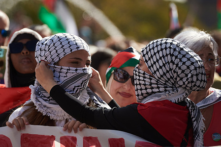 A Palestinian protester helps another woman put on a keffiyeh (a headscarf) during a demonstration. Thousands of people protested in the Navarrese capital in support of the Palestinian resistance and to demand the dissolution of the State of Israel.