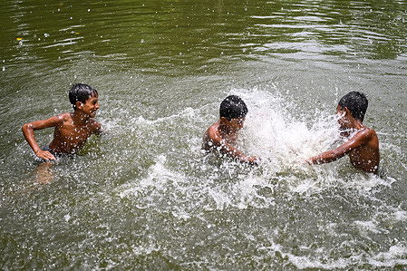 Children seen cooling off in a pond on a sweltering summer day.