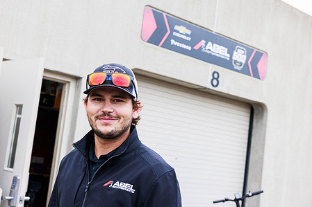 A teammate works on IndyCar driver R.C. Enerson (50) talks to fans outside the Team Abel garage on day one of practice for the 2023 Indy 500 at Indianapolis Motor Speedway in Indianapolis. The practice was rained out.