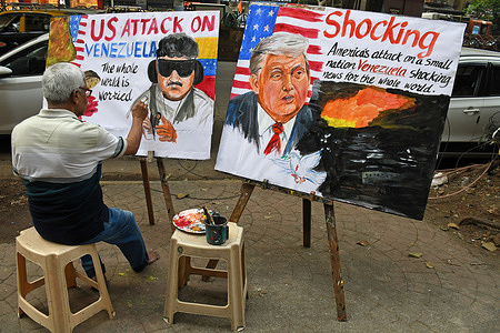 Teacher from Gurukul school of art paints a poster of 'US attack on Venezuela' depicting Venezuelan president, Nicolás Maduro and US president Donald Trump, outside their art school in Mumbai. United States launched airstrikes across northern Venezuela and areas around the capital city Caracas. President Nicolas Maduro and his wife Cilia Flores were captured by the US forces aimed to curb drug smuggling. US accused Maduro of drug smuggling and having links with drug cartels.