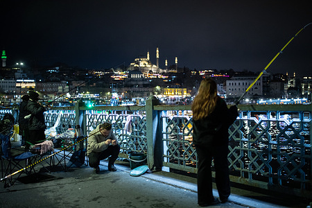 People seen fishing on the Galata Bridge in the evening hours.