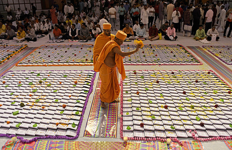 A priest sprinkles flower petals on books kept on the floor during Chopada (traditional account books) Pujan ceremony at the Swaminarayan temple in Mumbai. Chopada (traditional account books) Pujan is a ritual performed by Hindu business community during the Diwali festival to seek blessings for prosperity and success in the new financial year. People worship and seek blessings of goddess Lakshmi (goddess of wealth) and elephant-headed god Ganesha (for wisdom & auspicious beginnings).
