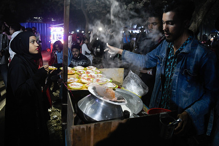 A street vendor prepares and serves Bhapa Pitha, a traditional winter delicacy made from rice flour, at Sohrawardy Udyan, a vibrant park in the heart of Dhaka. Originating from West Bengal, India, and Bangladesh.
