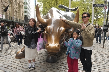 People take photos by the "Charging Bull" statue in the Financial District in Manhattan, New York City.