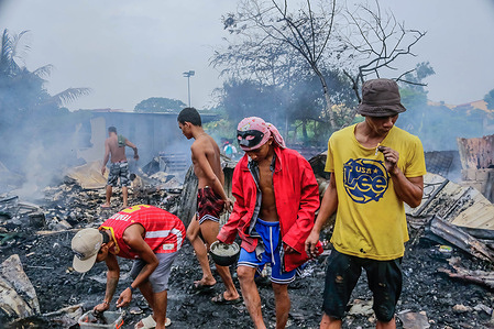 A group of fire victims search for reusable things during the aftermath. A fire that started at around 3pm hit Bato-bato 2 in Barangay Dolores, residential areas and left hundreds of individuals homeless. Philippines' Bureau Of Protection are still investigating the cause of the fire.
