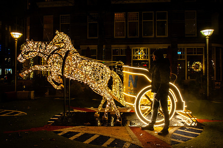 A man is seen watching a horse-drawn sleigh illuminated. Light sculptures in different shapes were placed around the city center to celebrate Christmas. This year, a light mural honored the life of Dutch artists, Van Lymborch Brothers, born in Nijmegen, in the mid-14th century.
