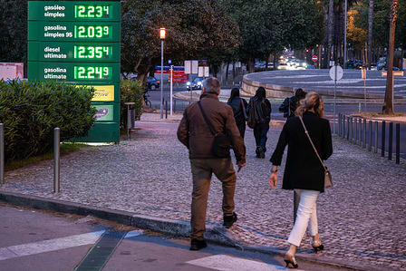 People walk past a fuel price board displayed at a gas station in Lisbon. The latest rise in fuel prices in Portugal once again highlights the energy marketís sensitivity to geopolitical tensions. Analysts note that recent confrontations between the United States and Iran have reignited oil price volatility, affecting prices across Europe.