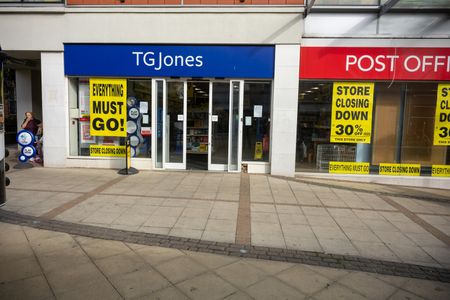 A woman stands outside the TG Jones store and Post Office on Brentwood High Street, where Everything Must Go and Store Closing Down 30% Off posters cover the windows. The TG Jones store and the High Street Post Office in Brentwood are closing as part of the TG Jones restructuring, leaving the Essex town centre without a Post Office.